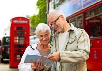 senior couple with map on london in city street family, age, tourism, travel and people concept - senior couple with map over london city street background